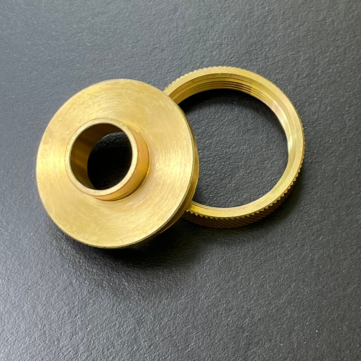 Two brass components on a gray background
