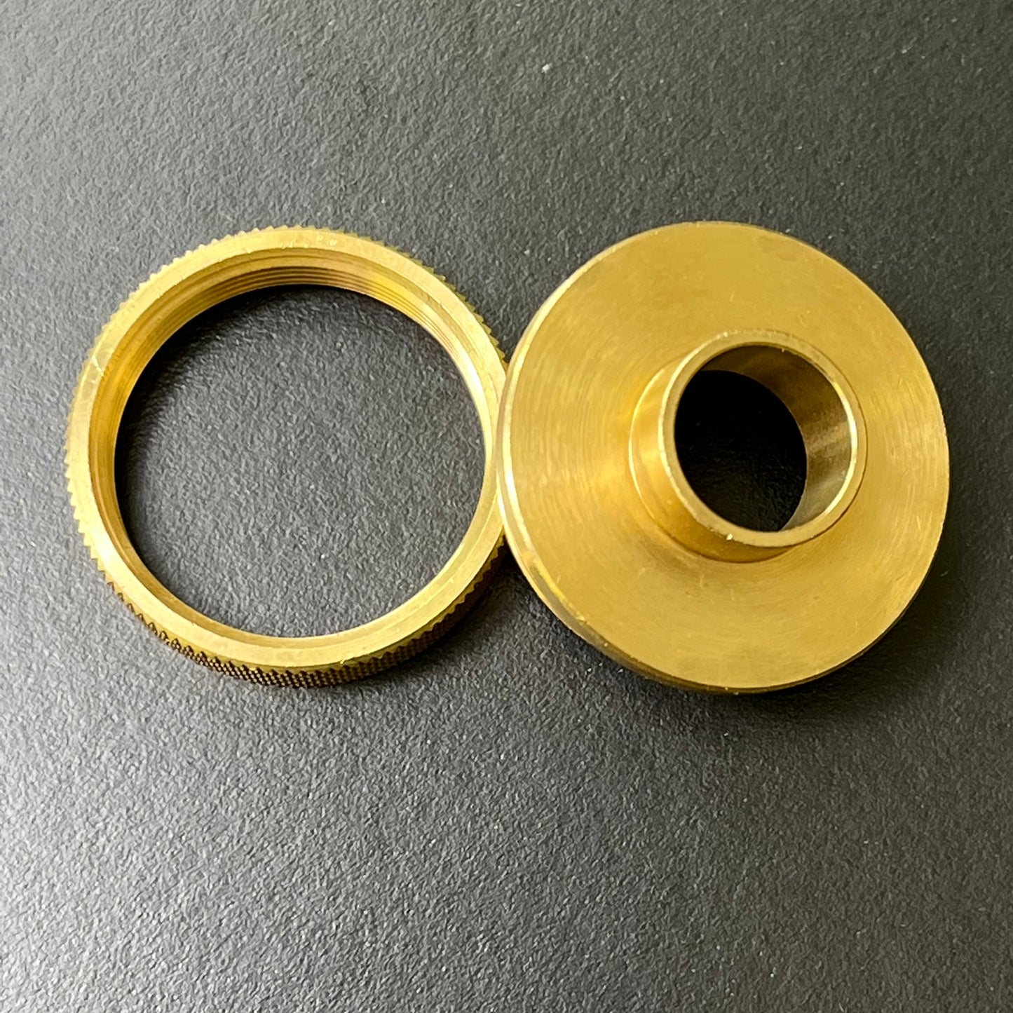 Two brass components on a gray background