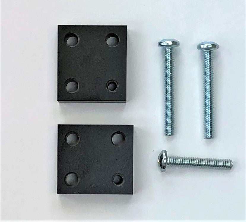 Two black metal riser blocks with four holes each and four silver screws laid out on a white surface.